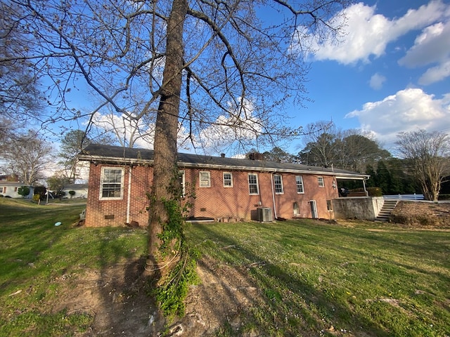 rear view of house featuring central AC, a yard, crawl space, brick siding, and stairs