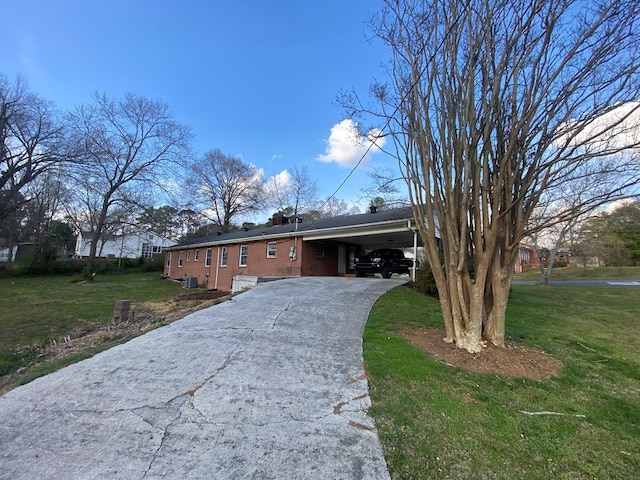 view of front of house with brick siding, an attached carport, driveway, and a front lawn