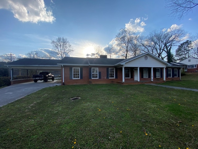 view of front of property with brick siding, a porch, concrete driveway, a front yard, and a chimney