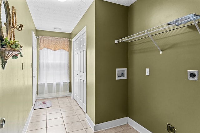 laundry area with electric dryer hookup, washer hookup, light tile patterned floors, and a textured ceiling