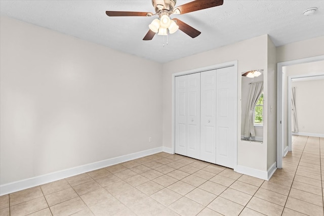 unfurnished bedroom with light tile patterned floors, a closet, a textured ceiling, and ceiling fan