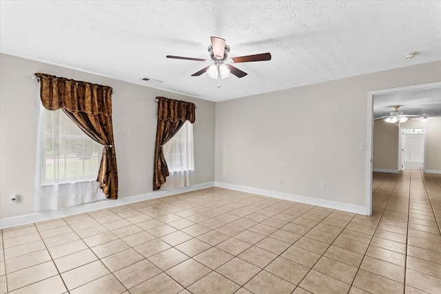 tiled empty room featuring a textured ceiling and ceiling fan