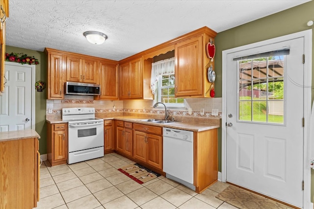 kitchen featuring sink, a textured ceiling, backsplash, and white appliances