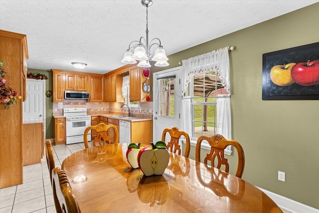 dining room with light tile patterned flooring, a chandelier, sink, and a textured ceiling