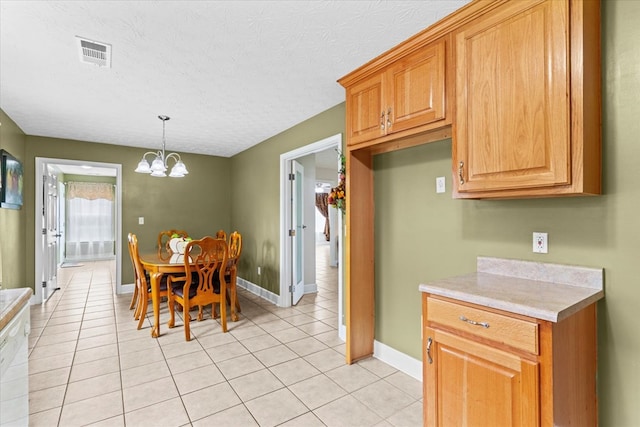 kitchen with light tile patterned floors, a textured ceiling, an inviting chandelier, and decorative light fixtures