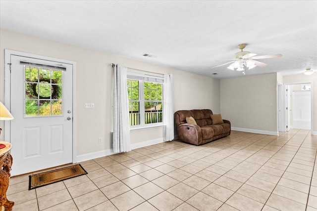 interior space featuring ceiling fan, a textured ceiling, and light tile patterned floors