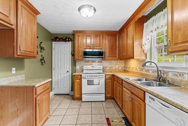 kitchen featuring light tile patterned flooring, sink, tasteful backsplash, a textured ceiling, and white appliances