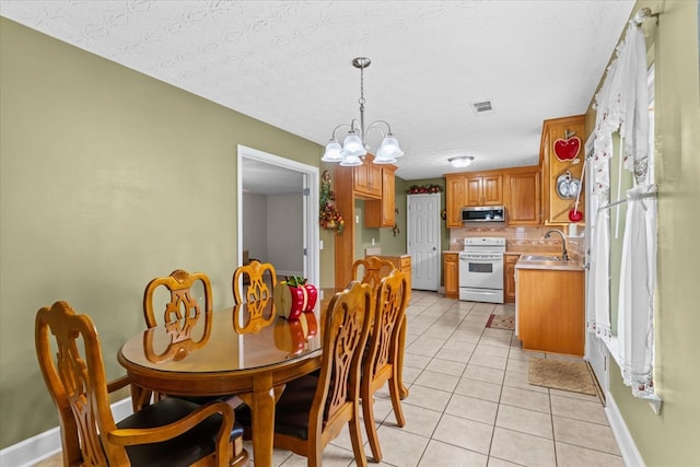 dining area featuring light tile patterned floors, a notable chandelier, sink, and a textured ceiling