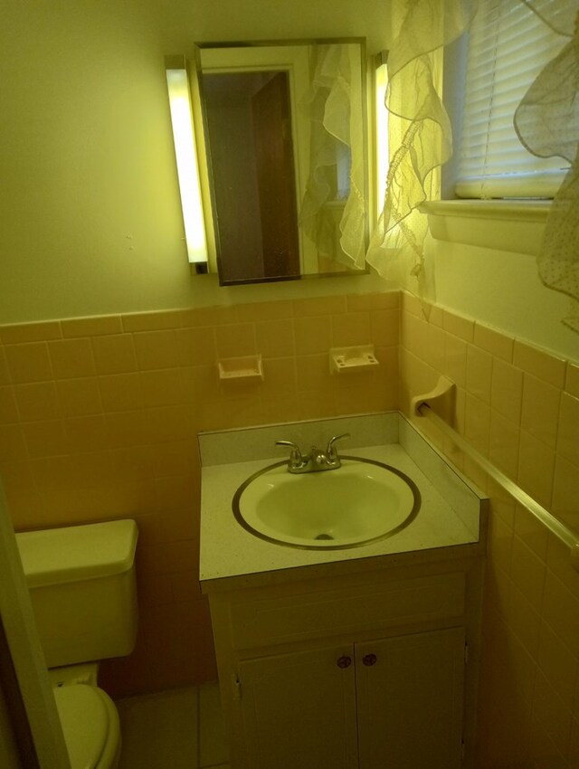 bathroom featuring vanity, toilet, and tile walls