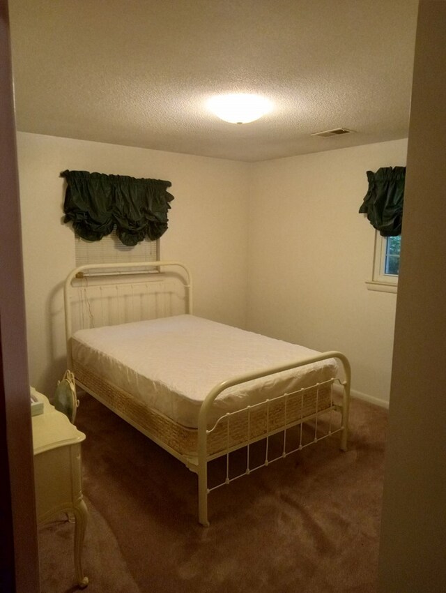 bedroom with a textured ceiling and dark colored carpet