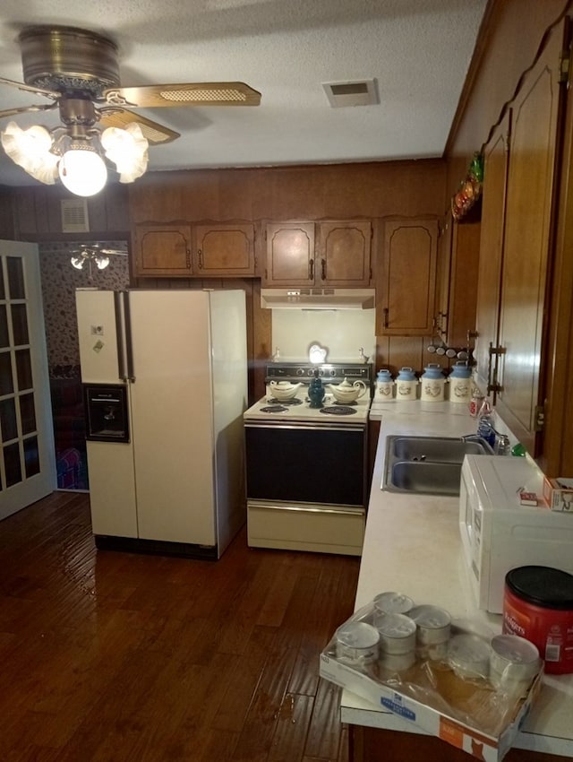 kitchen featuring sink, dark hardwood / wood-style flooring, white appliances, ceiling fan, and a textured ceiling