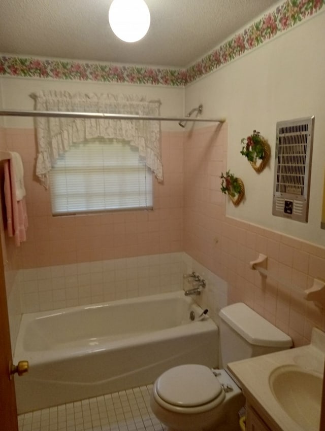 full bathroom with tile walls, tile patterned flooring, tiled shower / bath combo, toilet, and a textured ceiling