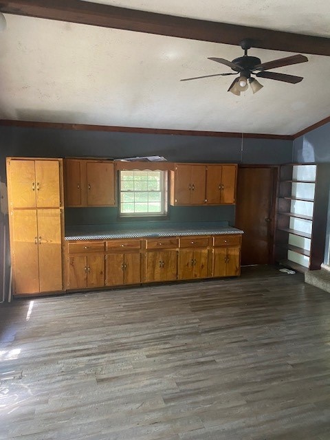 kitchen with dark hardwood / wood-style flooring, vaulted ceiling with beams, ornamental molding, and ceiling fan