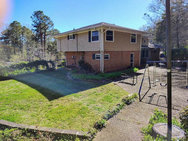 view of home's exterior featuring a trampoline, fence, brick siding, a patio, and a yard