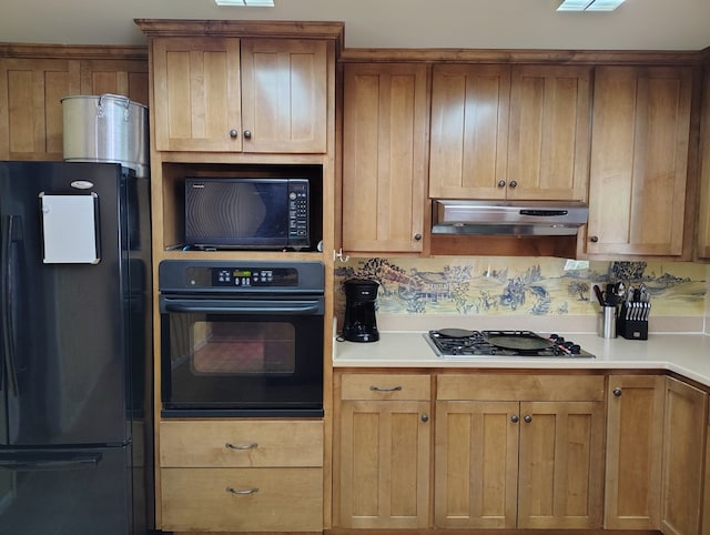 kitchen with under cabinet range hood, light countertops, black appliances, and brown cabinetry