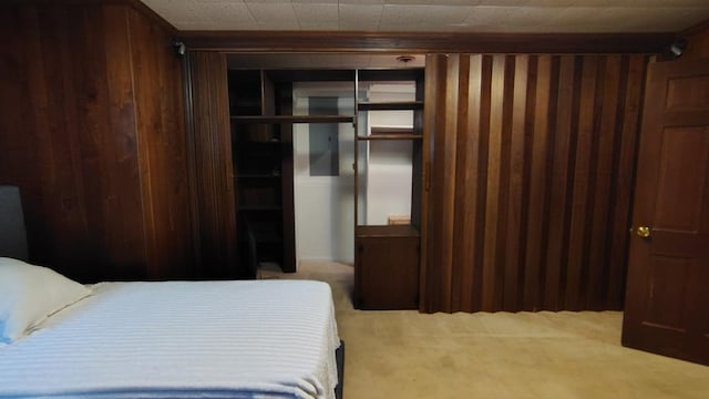 carpeted bedroom featuring a closet and wood walls