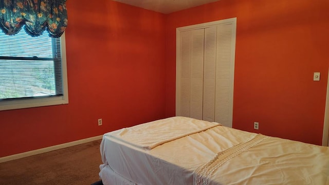 carpeted bedroom featuring baseboards and a closet