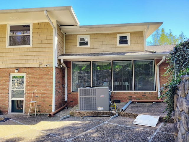 rear view of property with central AC unit and brick siding