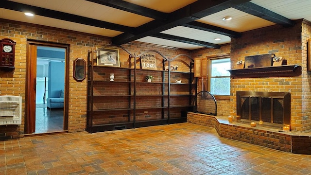 living area with beamed ceiling, a brick fireplace, brick floor, heating unit, and brick wall