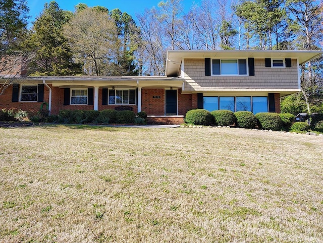 tri-level home with brick siding, a garage, and a front lawn