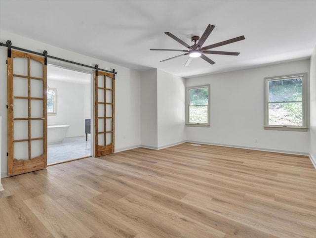 100 Tibbs Rd, Dalton, GA 30720 - unfurnished room with a barn door, light wood finished floors, and a ceiling fan