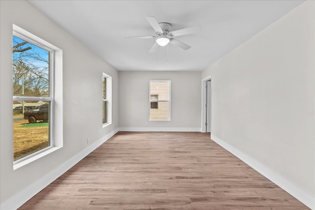 unfurnished room with ceiling fan, light wood-style flooring, and baseboards