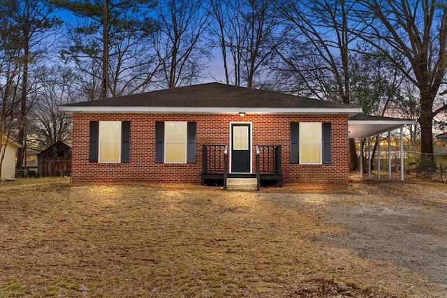 view of front facade with dirt driveway, an attached carport, and brick siding