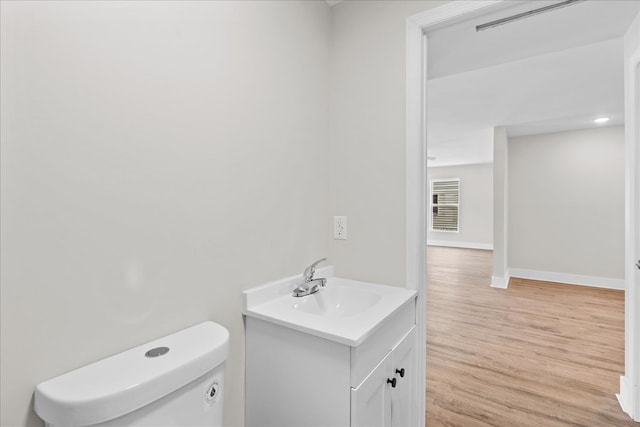 half bath featuring toilet, wood finished floors, vanity, and baseboards