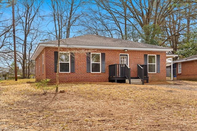 bungalow featuring a shingled roof and brick siding