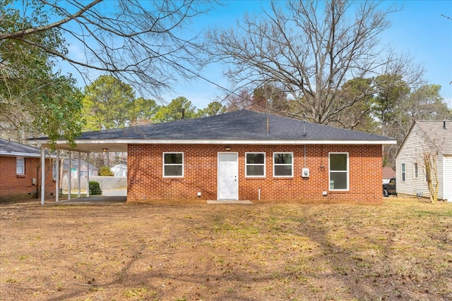 rear view of property with a yard, brick siding, and an attached carport