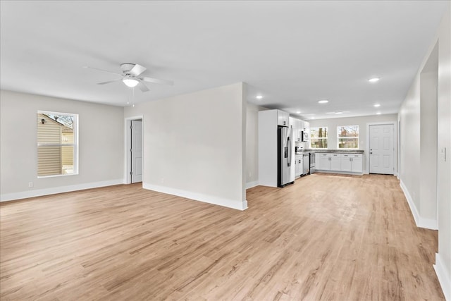 unfurnished living room with light wood finished floors, ceiling fan, and baseboards