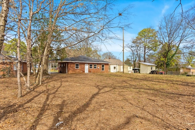 rear view of property featuring a carport, brick siding, and a lawn