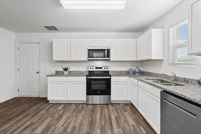 kitchen featuring appliances with stainless steel finishes, white cabinetry, sink, light stone counters, and dark wood-type flooring