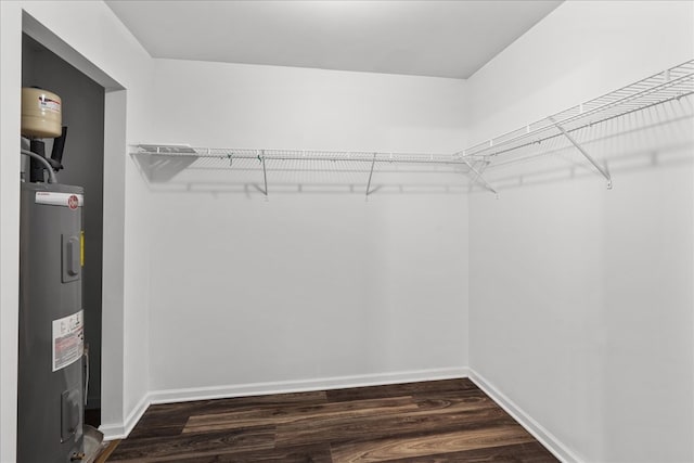 spacious closet with dark wood-type flooring and water heater