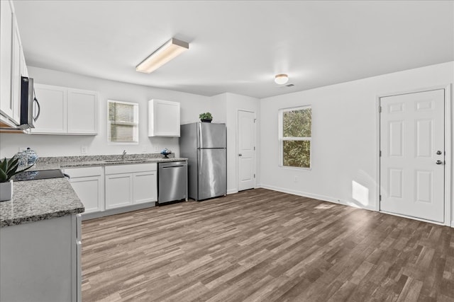 kitchen featuring sink, light stone counters, plenty of natural light, appliances with stainless steel finishes, and white cabinets