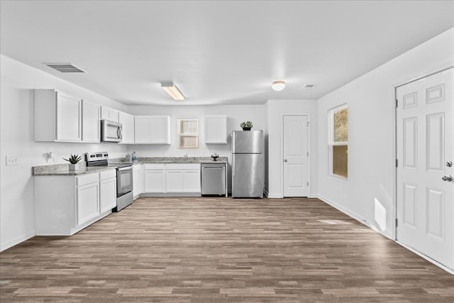 kitchen featuring sink, white cabinets, light stone counters, stainless steel appliances, and light wood-type flooring