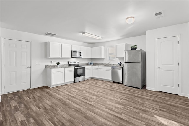 kitchen with sink, stainless steel appliances, white cabinets, and light wood-type flooring