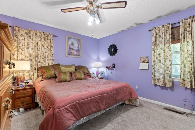 bedroom featuring ceiling fan, a textured ceiling, visible vents, baseboards, and carpet flooring