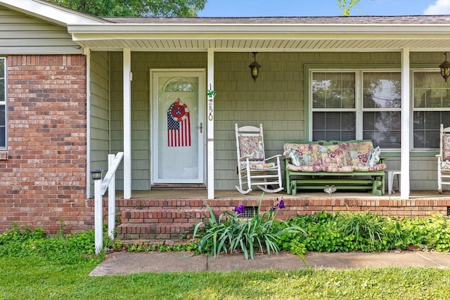 property entrance with a porch and brick siding