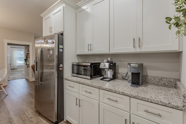 kitchen with white cabinets, light stone countertops, light wood-style floors, and stainless steel appliances