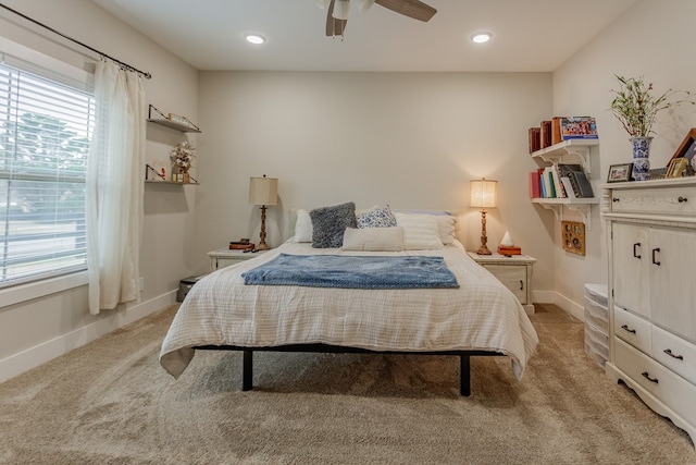 bedroom with a ceiling fan, light carpet, baseboards, and multiple windows