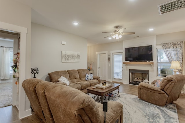 living room with ceiling fan, a fireplace, visible vents, recessed lighting, and wood finished floors
