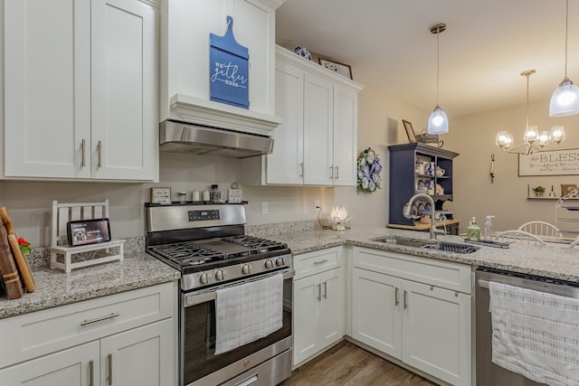kitchen featuring an inviting chandelier, white cabinetry, appliances with stainless steel finishes, range hood, and a sink