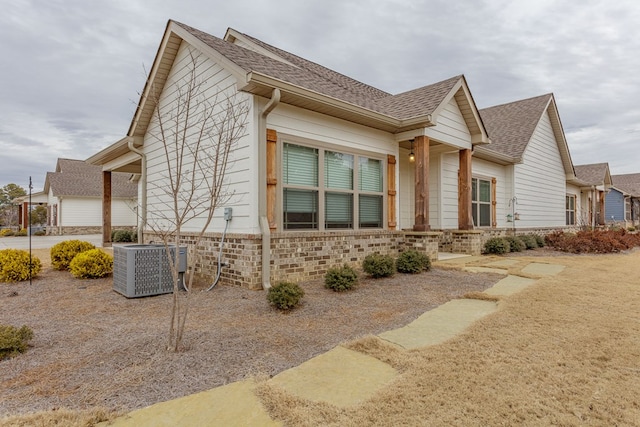 view of property exterior featuring roof with shingles and central AC