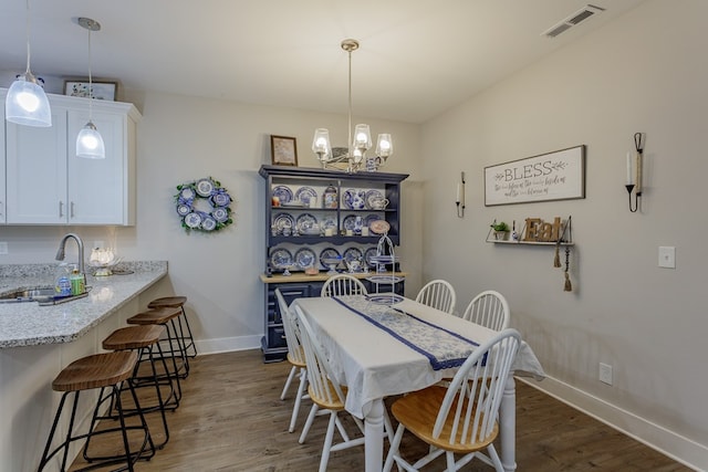 dining area featuring a chandelier, wood finished floors, baseboards, and visible vents