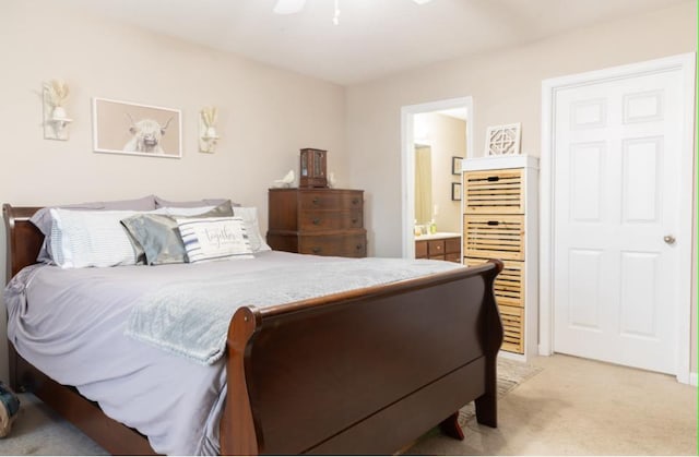 bedroom with ceiling fan, light colored carpet, and ensuite bath