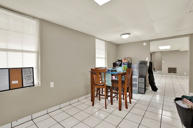 tiled dining area featuring a drop ceiling and heating unit