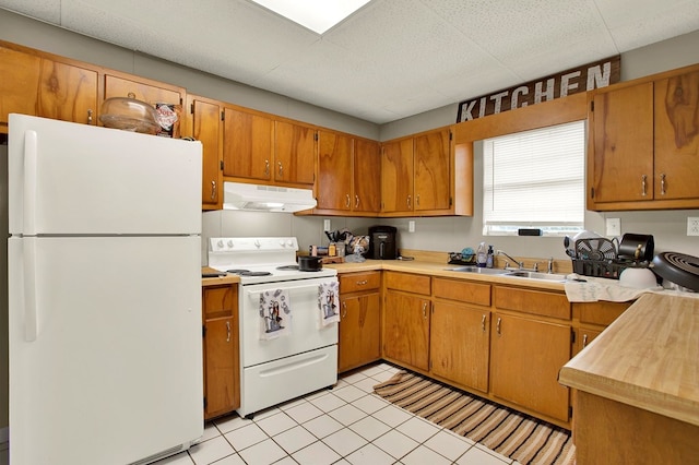 kitchen featuring light tile patterned flooring, white appliances, and sink