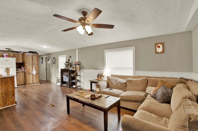 living room featuring ceiling fan, lofted ceiling, dark wood-type flooring, and a textured ceiling