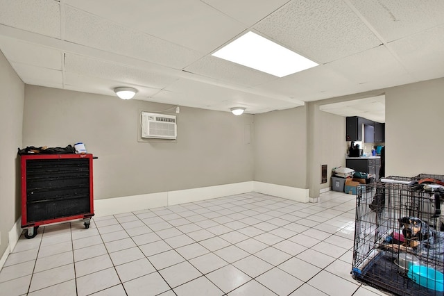 basement featuring light tile patterned flooring, a paneled ceiling, and a wall mounted AC